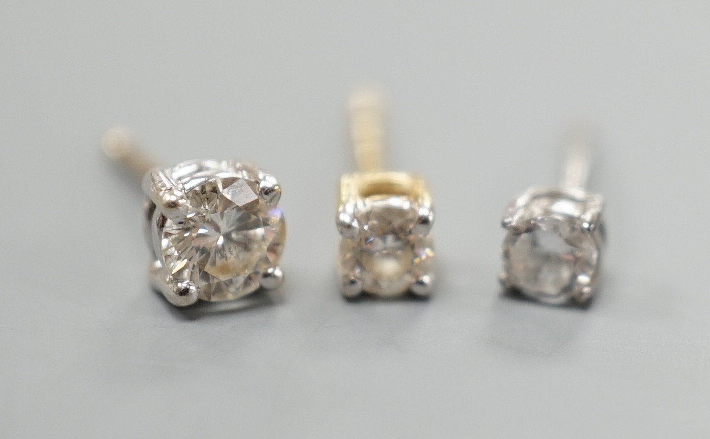 Two odd diamond set ear studs, the stones of various sizes and one paste set ear stud, gross weight 1.3 grams.